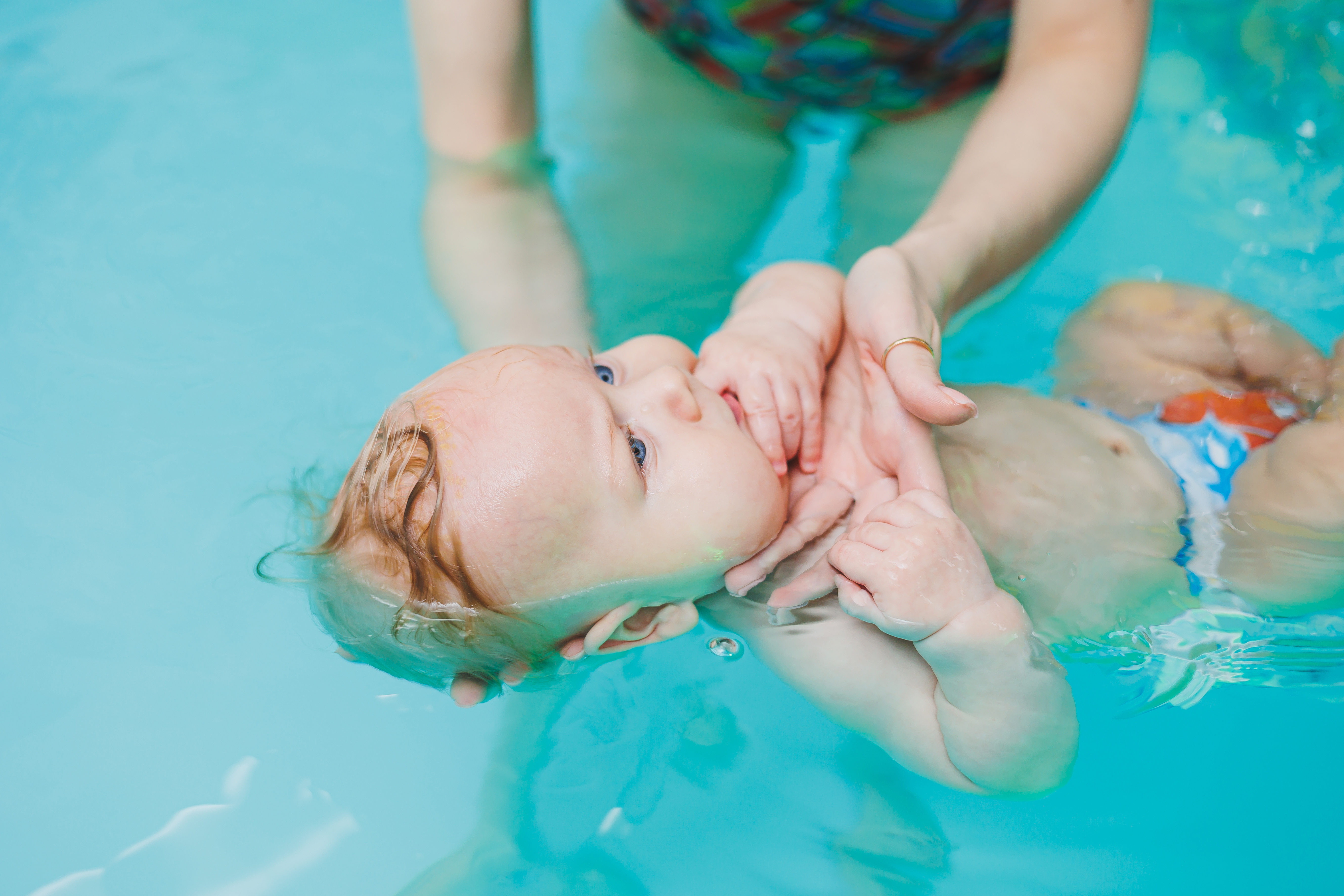 Monitor acompañando a un niño durante una clase de natación